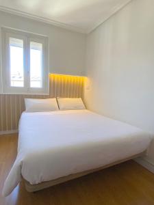 a large white bed in a room with two windows at Apartamento en la Catedral in Burgos