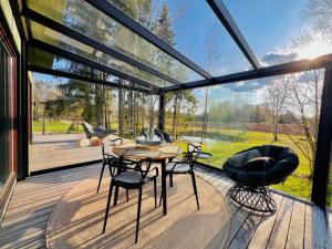 una casa in vetro con tavolo e sedie su una terrazza di House and sauna where city comforts meet nature a Aiaste