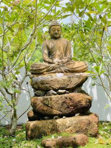 een standbeeld van een Boeddha zittend op een rots bij New Cinnoman Villa in Bentota