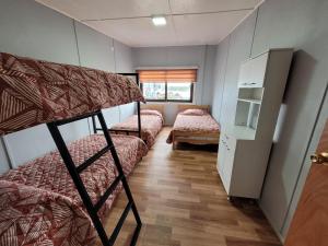 a room with three bunk beds and a window at Hospedaje Alimar in Frutillar