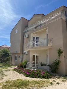 a building with a balcony and flowers in front of it at Apartmani Šaldi in Pakoštane