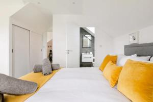 Un dormitorio con una gran cama blanca con almohadas amarillas. en Ashwood bed and breakfast, en Truro