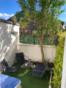 un patio con sillas, una mesa y un árbol en La Jeannette - séjour premium tout inclus dans une maison proche gare-centre avec lit 160 Emma, terrasse, parking et plus, en Châteauroux
