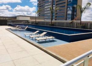 a swimming pool with lounge chairs in a building at Lazer e shopping Apt DF Plaza in Brasília