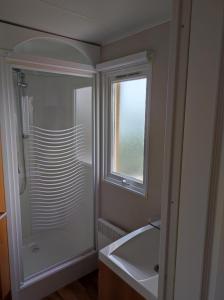 a bathroom with a shower and a sink and a window at Mobil home 2 chambres vue direct sur mer in Le Portel