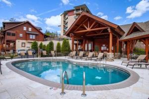 uma piscina de resort com cadeiras e um edifício em Cozy Cabin in the Smokies!!! Fully Furnished and complete with community indoor and outdoor pools and spas, game and fitness rooms as well as a private Hot Tub em Pigeon Forge