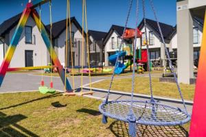 a playground with a swing in a park at Domki Nord Breeze z podgrzewanym basenem in Władysławowo