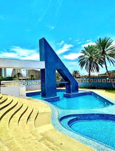 a swimming pool with a blue building with palm trees at Apartamento Isla de Margarita,Porlamar, Pampatar in Porlamar