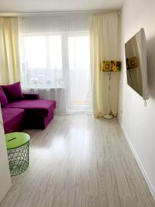 a living room with a purple couch and a window at Seaview Flat in Liepāja