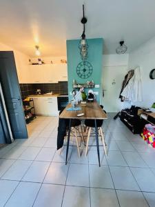 eine Küche mit einem Tisch mit Stühlen und einer Uhr an der Wand in der Unterkunft Key Home Leman -T2 cosy-portes de Genève-jardin in Étrembières