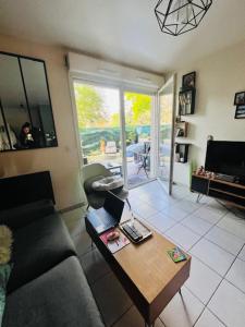 ein Wohnzimmer mit einem Sofa und einem Tisch mit einem Laptop in der Unterkunft Key Home Leman -T2 cosy-portes de Genève-jardin in Étrembières