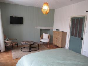 a bedroom with a bed and a chair and a tv at Appartement village in Simorre