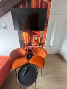 Cette chambre dispose de 2 chaises et d'une télévision murale. dans l'établissement Esprit Italie, joli studio au coeur de Mulhouse, à Mulhouse