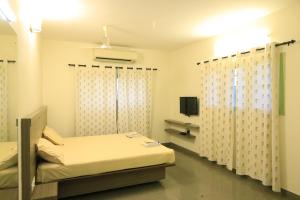 a hospital room with two beds and a tv at Transit Nest - Homestay Near Madurai Airport in Madurai