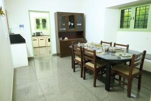 a dining room with a table and chairs and a kitchen at Transit Nest - Homestay Near Madurai Airport in Madurai