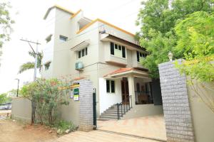 una casa blanca con una valla delante en Transit Nest - Homely stay Near Madurai Airport, en Madurai