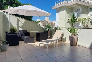 een patio met stoelen, een parasol en een tafel bij Apê Canto das Gaivotas Ingleses Norte in Florianópolis