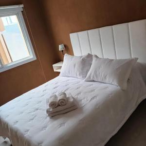 a white bed with two towels on top of it at Bahia Blanca Estudio con Estacionamiento in Bahía Blanca