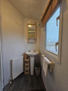La salle de bains est pourvue d'un lavabo et d'une fenêtre. dans l'établissement Tattershall lakes hot tub lodge breaks, à Tattershall