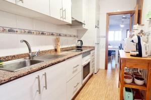 a white kitchen with a sink and a counter at Agréable appartement avec piscine commune in San Pedro del Pinatar