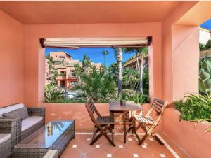 eine Terrasse mit einem Tisch und Stühlen sowie einem großen Fenster in der Unterkunft Lovely Elviria Apartment 200m from the beach in Marbella