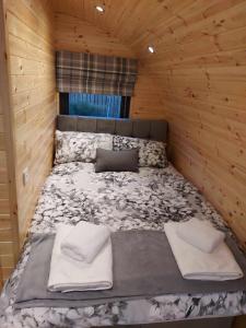 1 cama en una cabaña de madera con 2 almohadas en Silver Birch Bothy, en Spean Bridge