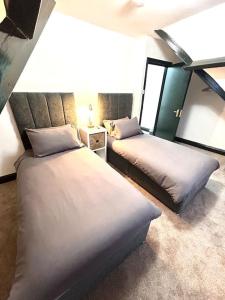 Un dormitorio con dos camas y una lámpara sobre una mesa. en Luxurious Bridlington villa sleeps 13, en Bridlington