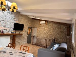 uma sala de estar com um sofá e uma parede de pedra em Casa de La Serra em Montblanc