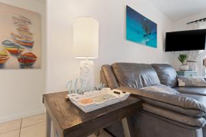 ein Wohnzimmer mit einem Ledersofa und einem Tisch in der Unterkunft Villas On The Gulf L1- Ocean view steps to beach! in Pensacola Beach