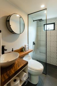 ein Badezimmer mit einem Waschbecken, einem WC und einem Spiegel in der Unterkunft EyB Chalets in Heredia