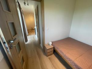 a small bedroom with a bed and a door at Przytulny domek na Mazurach - Jeziorowskie k. Kruklanek in Jeziorowskie