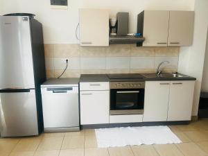 a kitchen with white cabinets and a refrigerator at Orange Tree Garden in Kastel Stafilic