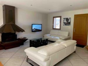 sala de estar con sofá blanco y TV en Maison de village à 5 minutes de St Lary Soulan, en Saint-Lary-Soulan