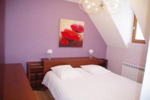 1 dormitorio con 1 cama y una pintura de flores rojas en Maison de village à 5 minutes de St Lary Soulan, en Saint-Lary-Soulan