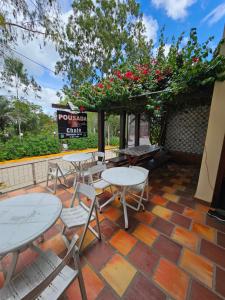 d'une terrasse avec des tables, des chaises et des fleurs. dans l'établissement Pousada dos Filhos, à Arcoverde