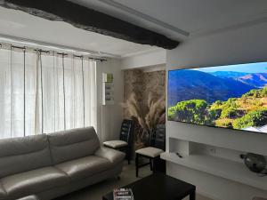 sala de estar con sofá y TV de pantalla plana en La Verdière, en Cesny-Bois-Halbout