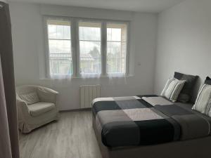 1 dormitorio con 1 cama, 1 silla y ventanas en La Verdière, en Cesny-Bois-Halbout