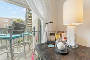 a table with a lamp and books and a chair at Villas On The Gulf L1- Ocean view steps to beach! in Pensacola Beach