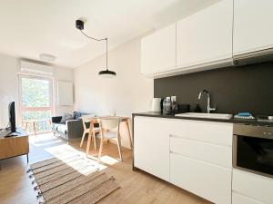 a kitchen with white cabinets and a living room at Aparthotel Weissa 7 in Krakow