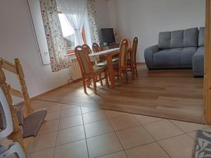 a living room with a table and chairs and a couch at Domek na skraju lasu in Płaska