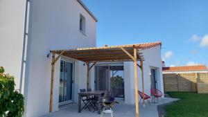 eine Terrasse mit einer hölzernen Pergola und einem Tisch in der Unterkunft L ancrage - proche de la plage in Brem Sur Mer