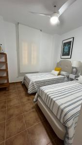two beds in a room with white walls and tile floors at Apartamento 2 dormitorios Isla Canela in Isla Canela +43 photos