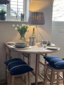 een tafel met een lamp en een tafel met stoelen bij Cosy Coastal Cottage in the heart of Salcombe. in Salcombe