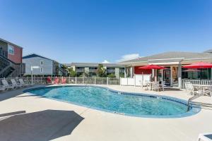 einen Pool mit Tischen, Stühlen und Sonnenschirmen in der Unterkunft Villas On The Gulf L1- Ocean view steps to beach! in Pensacola Beach