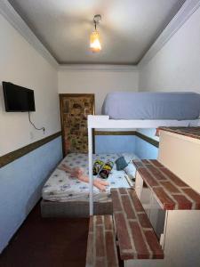a small room with a bunk bed and a table at Suíte Garden in Praia Grande