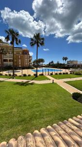 a park with palm trees and a swimming pool at Apartamento 2 dormitorios Isla Canela in Isla Canela