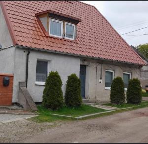 a house with an orange roof with bushes in front of it at Apartament u Krystynki in Kętrzyn