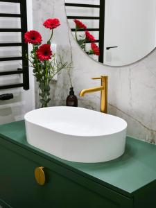 a white sink on a green counter with red flowers at Sage Apartment in Kraków