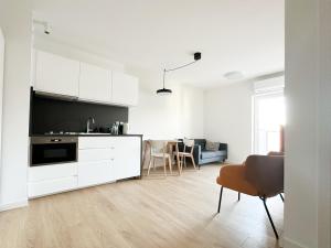 kuchnia z białymi szafkami i salon w obiekcie Aparthotel Weissa 7 w Krakowie