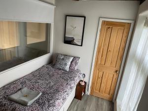 a small bedroom with a bed and a wooden door at Artist and musicians chapel project in Briston